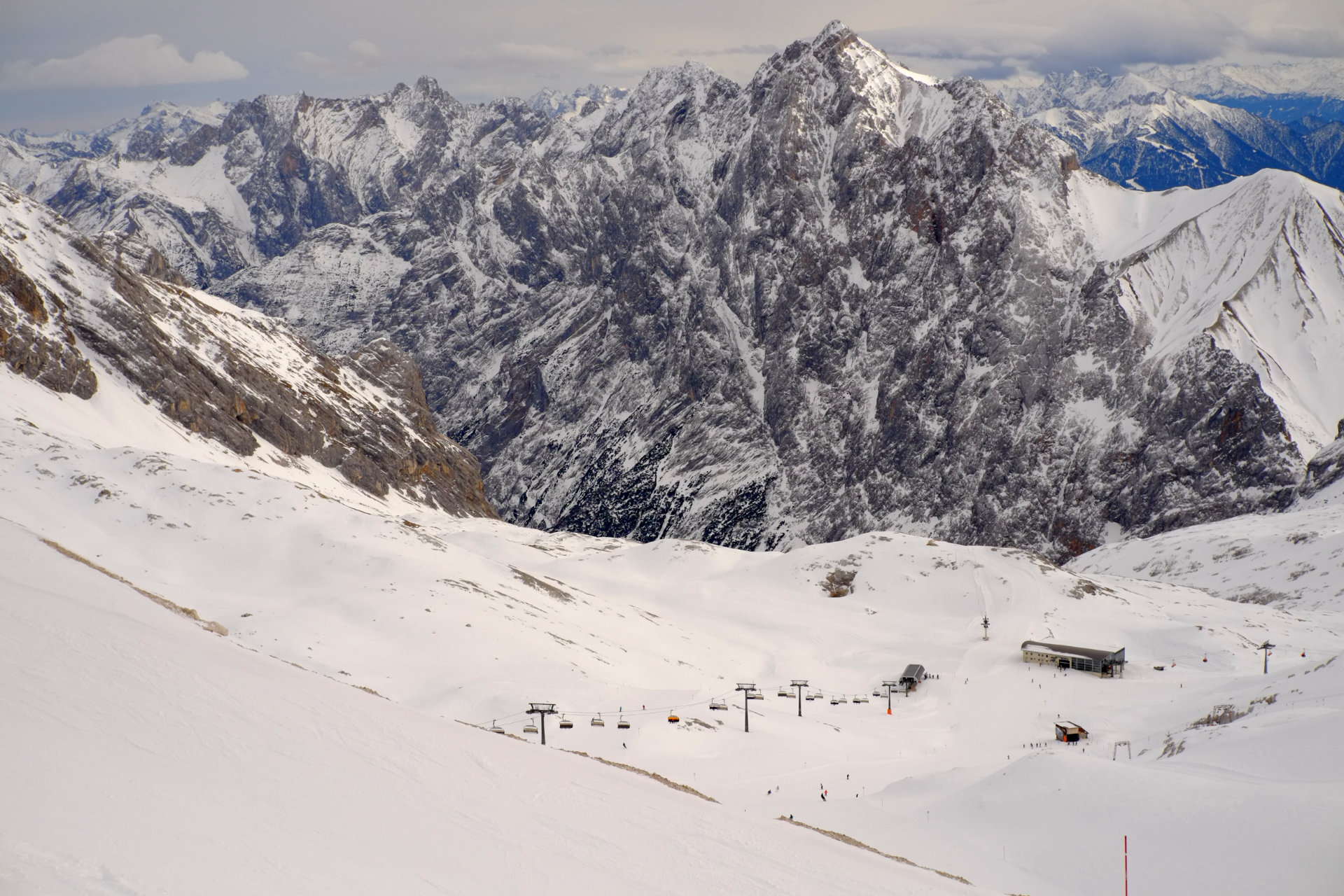 A photo of skiing slopes going down into the valley with big snowy rocky mountains in the distance.