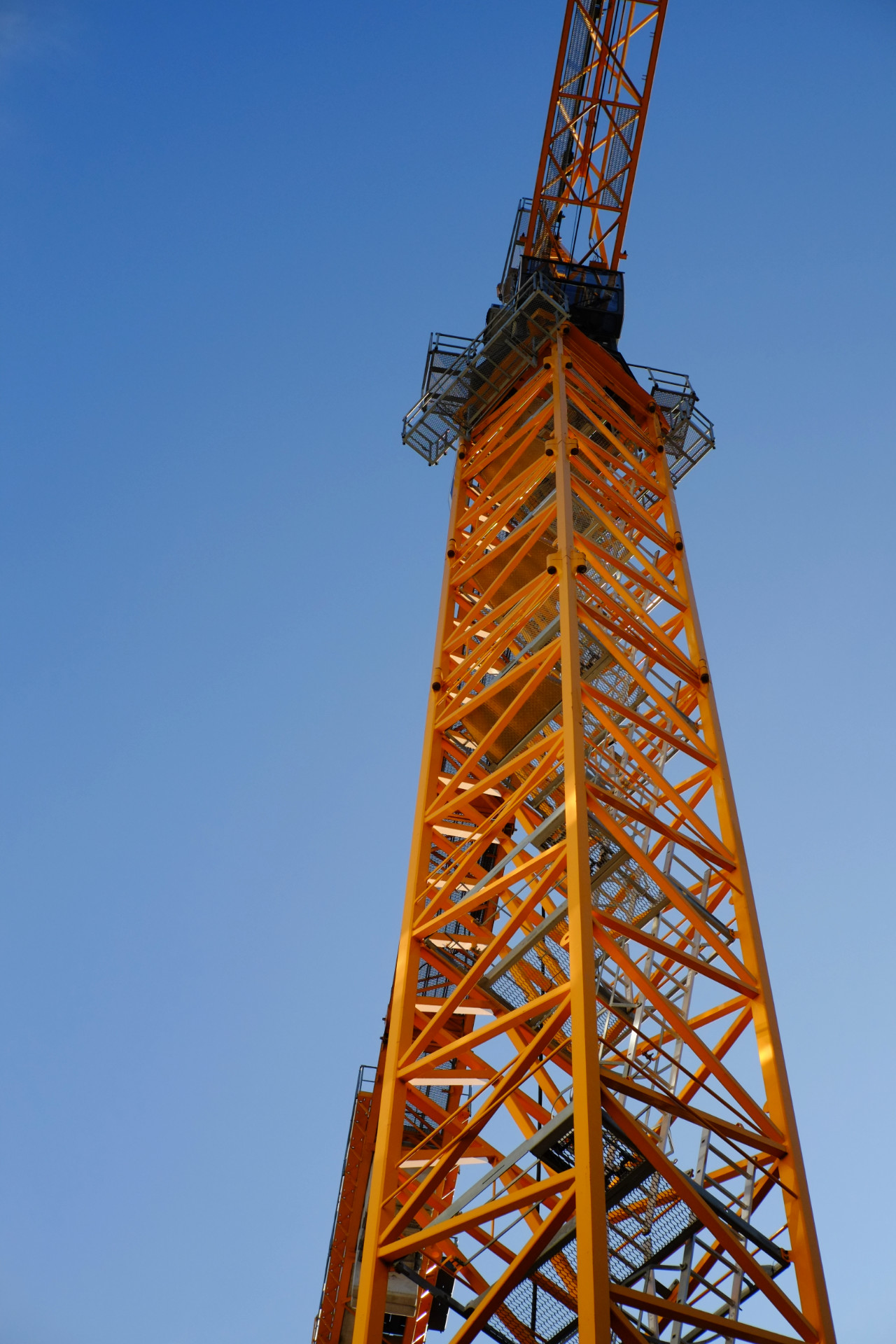 A photo of yellow construction crane from underneath with the blue sky in the background.
