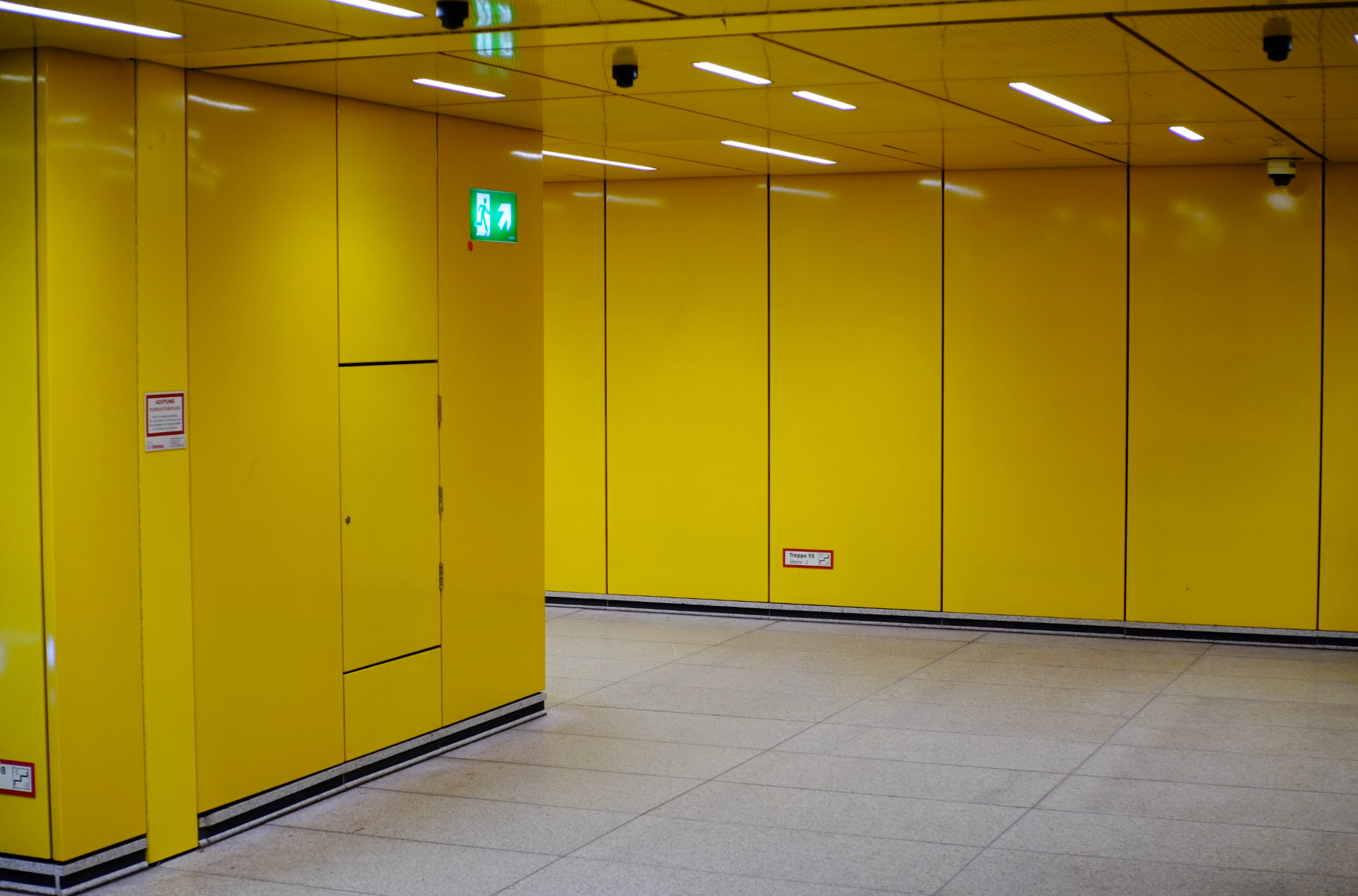 A photo of a metro station hall with bright yellow plastic wall tiles.