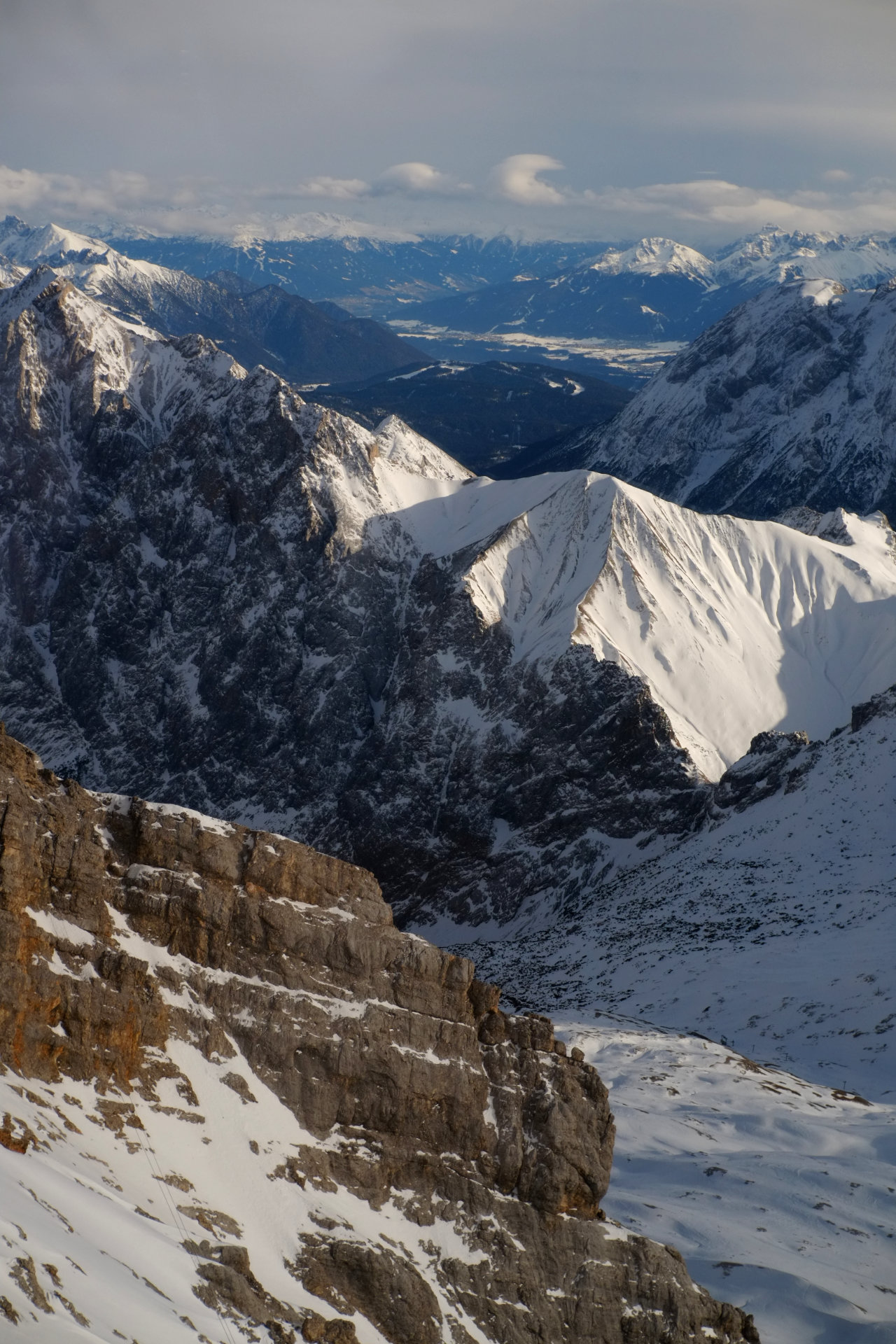 A photo of a snowy mountain valley with a brown rocky cliff blocking the view.