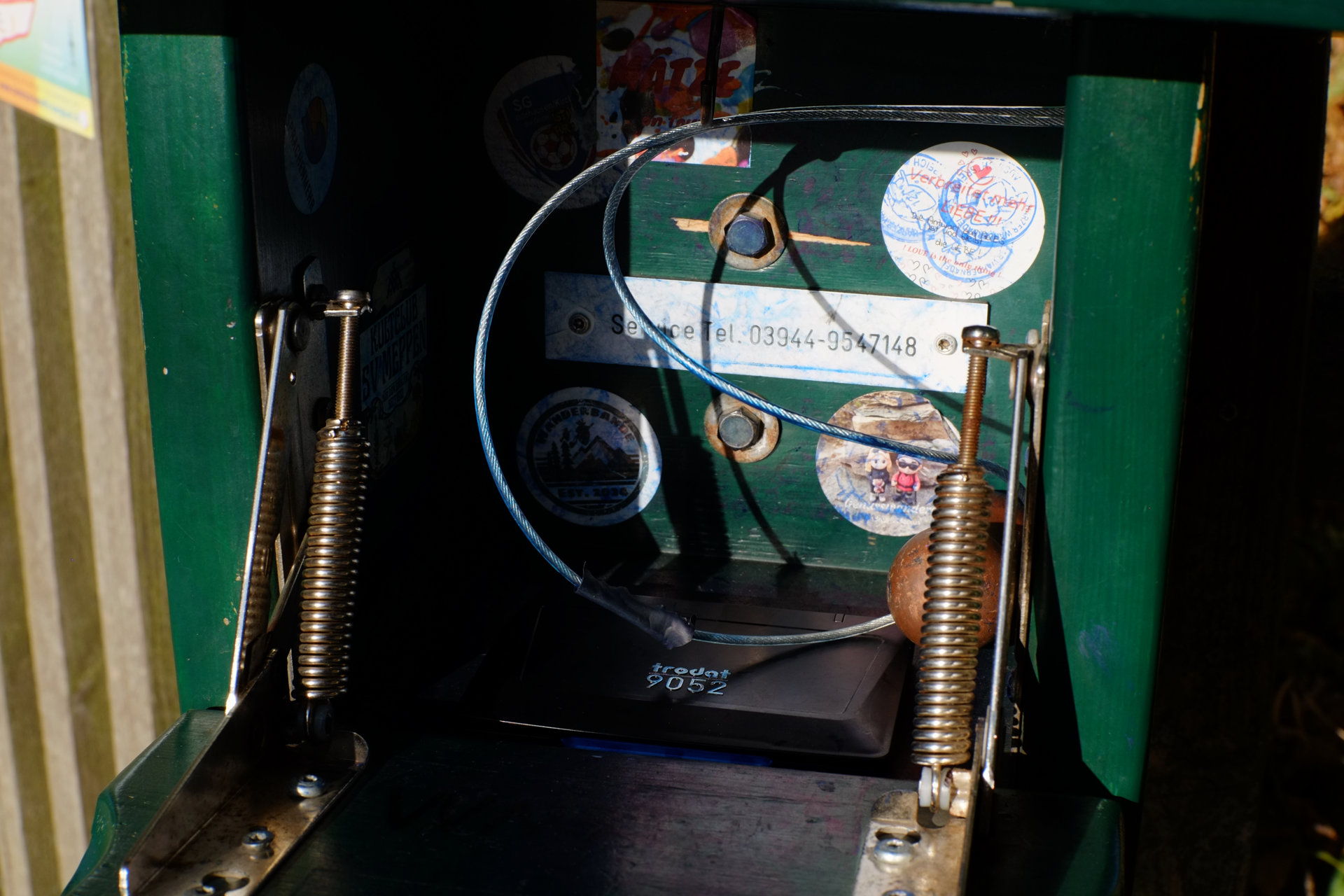 A photo of an opened green woden box with the inside decorated with several stickers, with a wooden stamp and a black plastic ink sponge box inside.