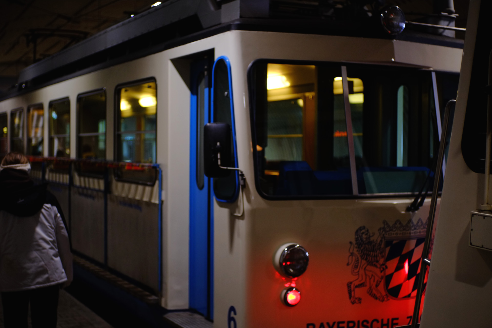 A photo of a white and blue cogtrain car from the outside, while it's staying in a tunnel at it's last stop.