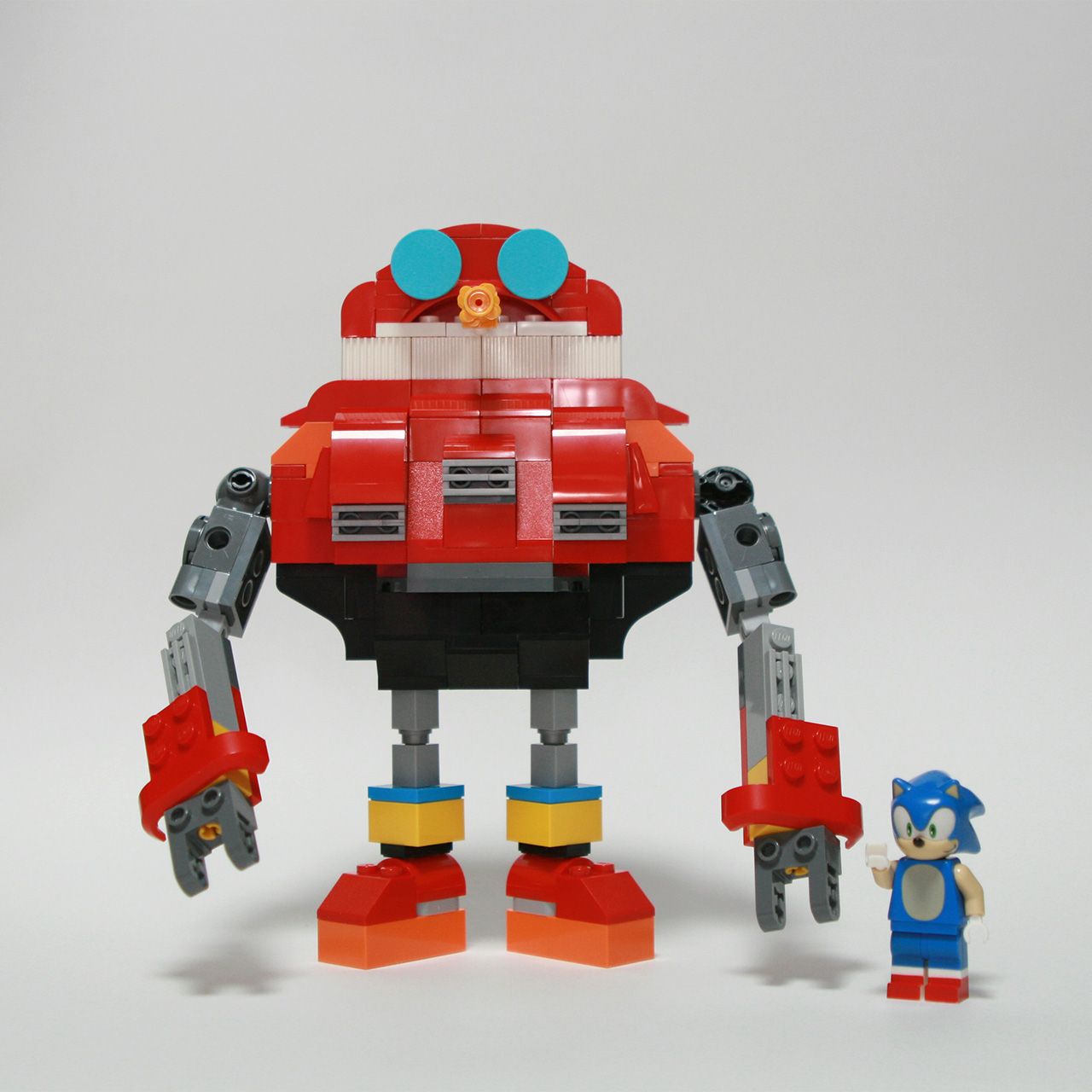A photo of an Egg Pawn from the video game Sonic Heroes (2003) built with LEGO, with Sonic the Hedgehog LEGO minifigure standing next to it.