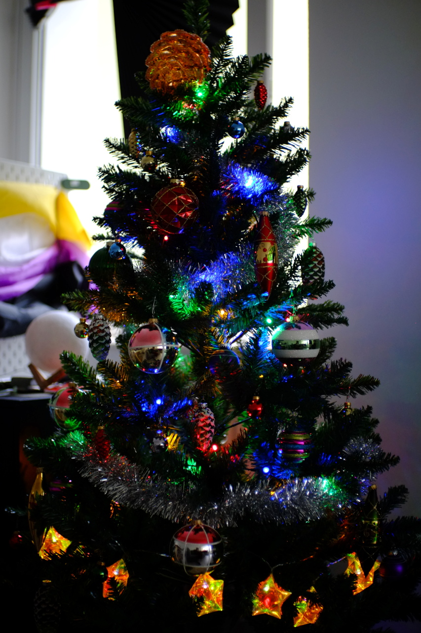A photo of a plastic spruce decorated with glass and plastic ornaments and two colorful electric garlands.