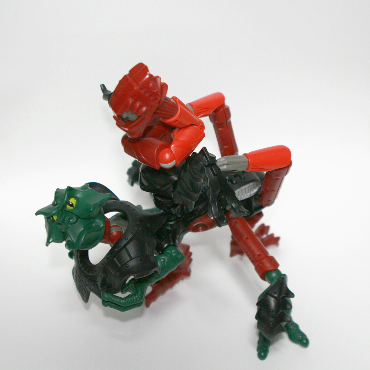 A photo of a LEGO Galidor MOC build: an amalgamation of two alien looking bodies, the green body protruding forward from the red body with several limbs and a long neck with a small head on top.