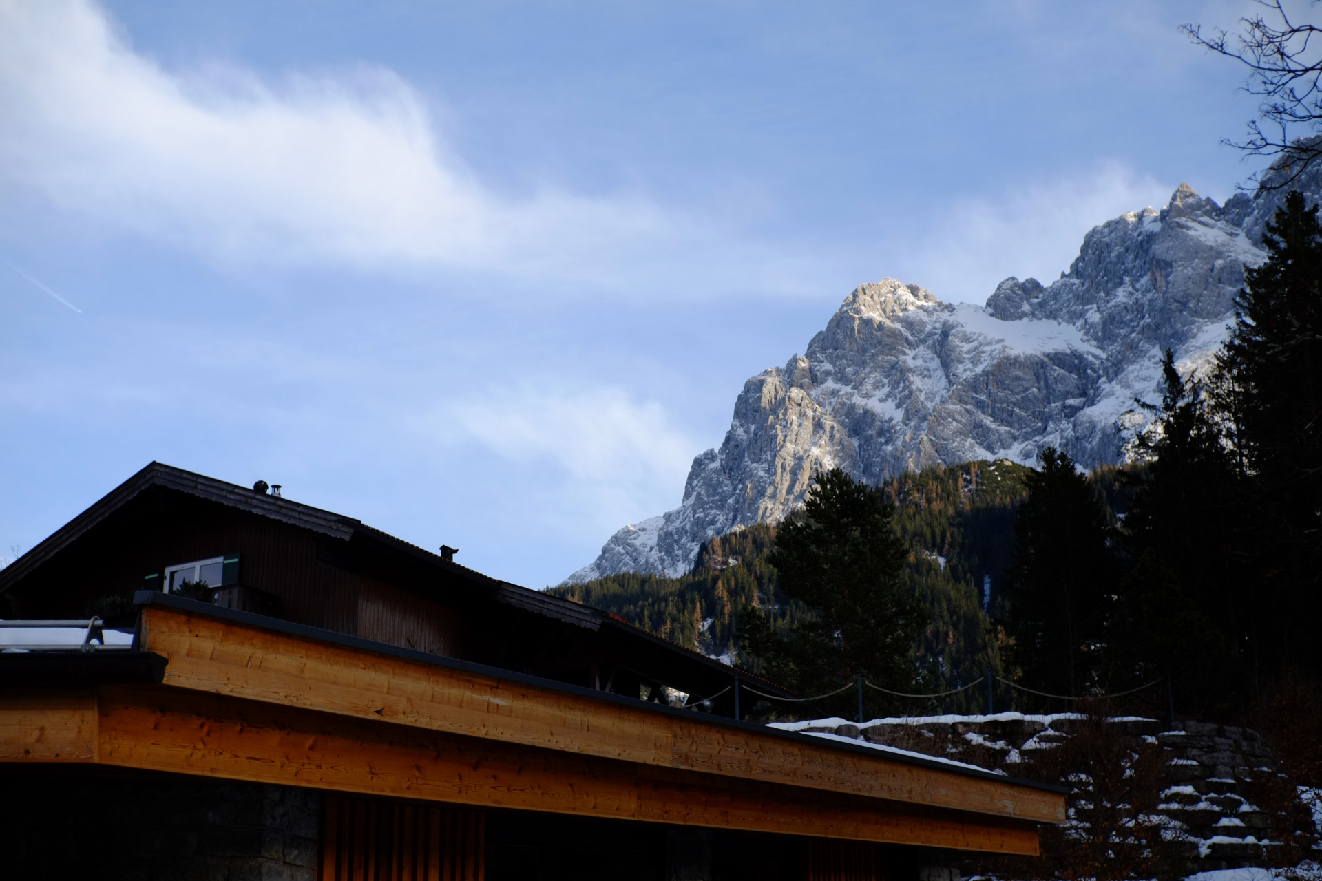 A photo of a brown wooden roof with snowy cliffs high above in the background