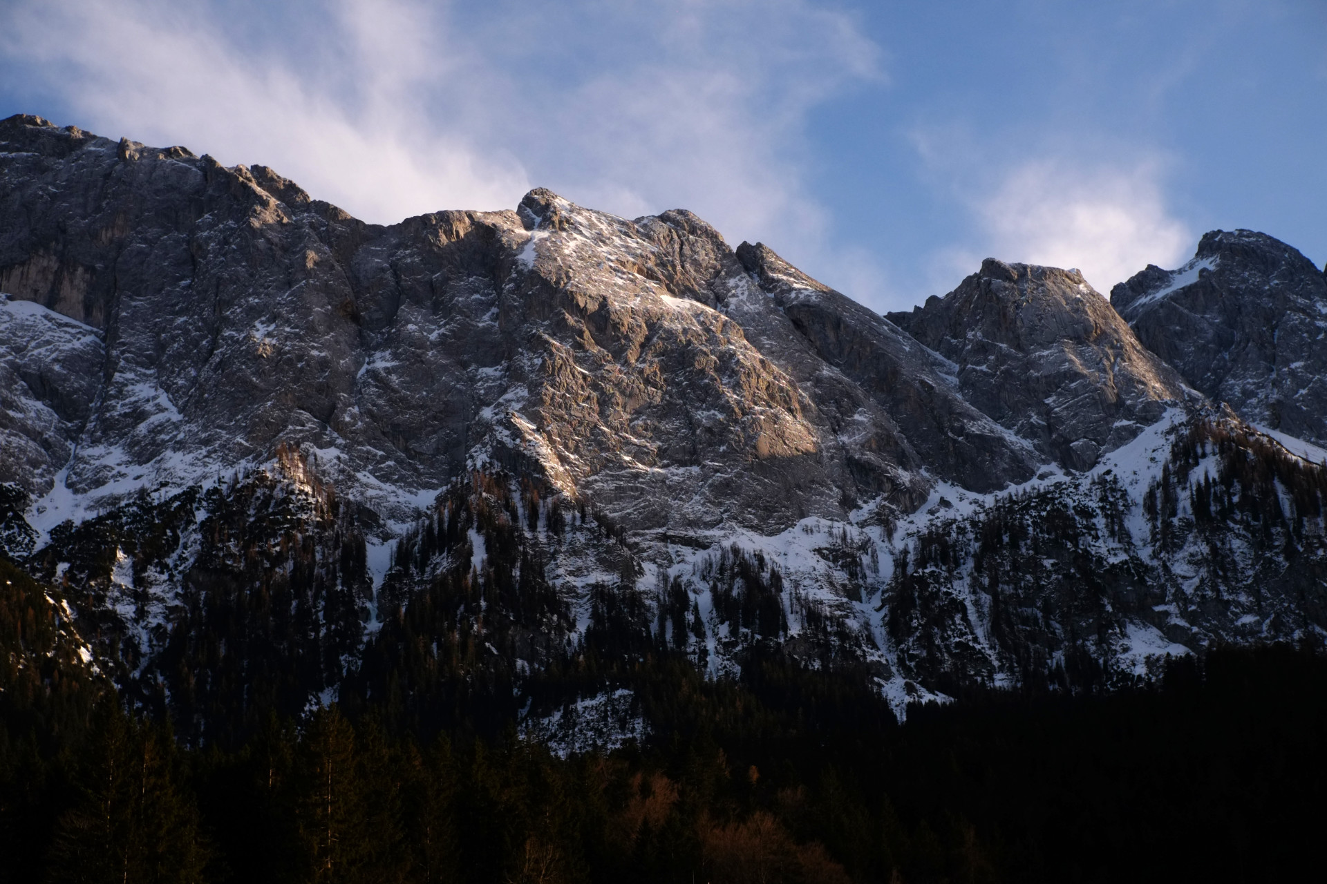 A photo of mountain cliffs  from below lit by the evening sun.