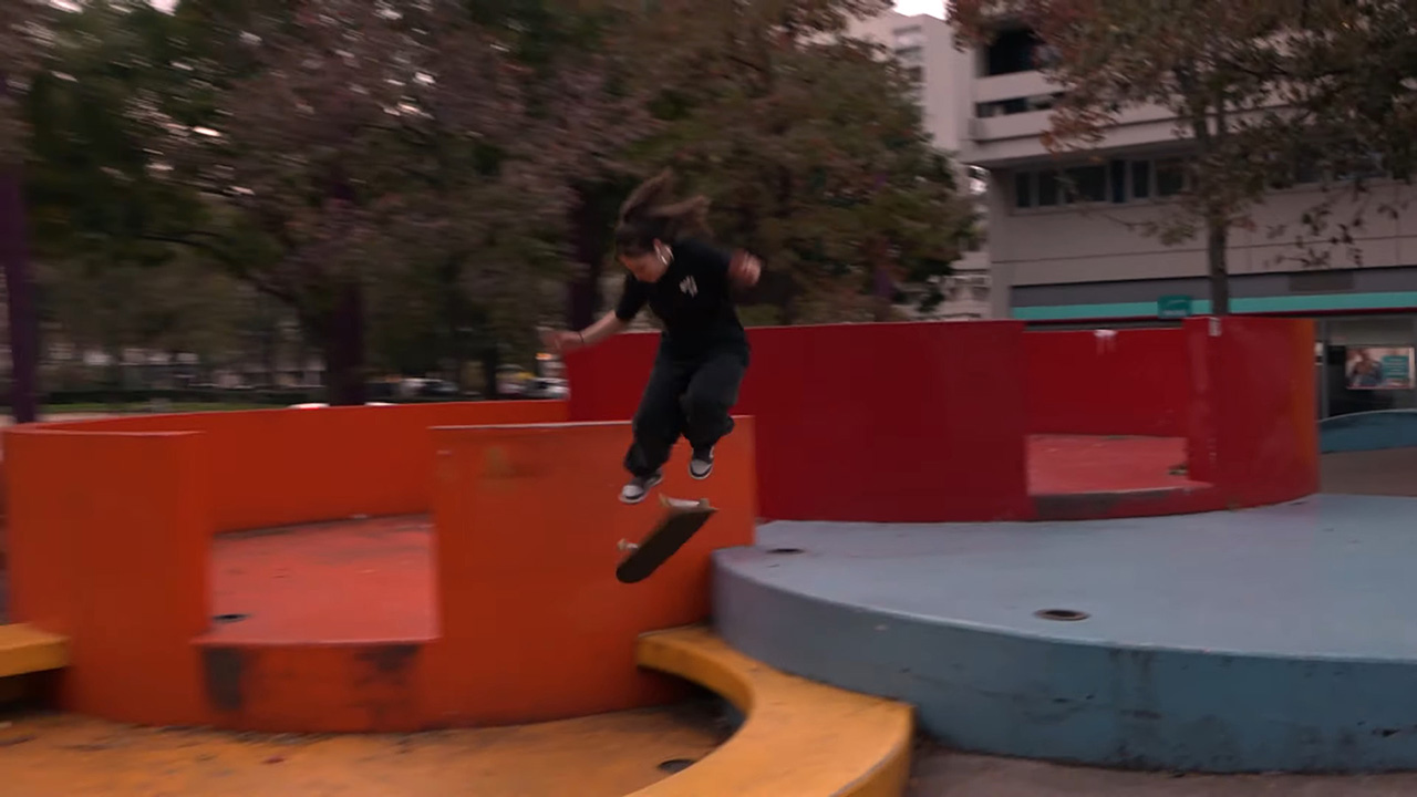 A photo of a skater in black outfit jumping from blue concrete platform down onto an orange one.