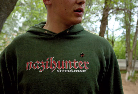 A close-up photo of a man wearing a green hoodie with the Nazihunter logo